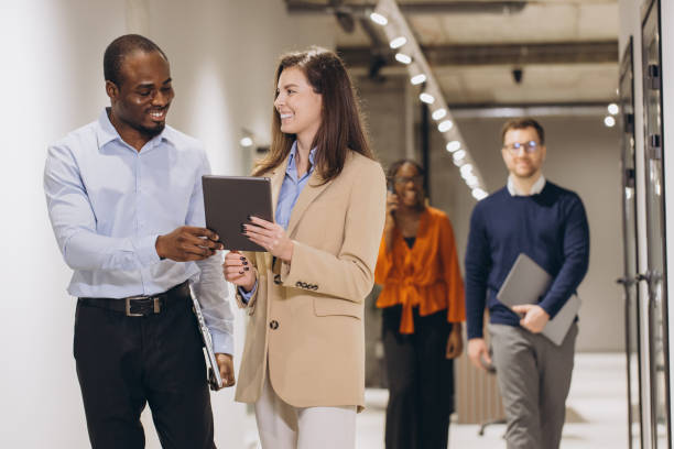 istock Business colleagues using digital tablet, discussing work in office corridor, teamwork and collaboration in modern workplace 2198573273