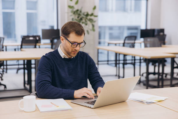 istock Professional working on laptop at sleek office desk, focusing on screen while typing 2198573392