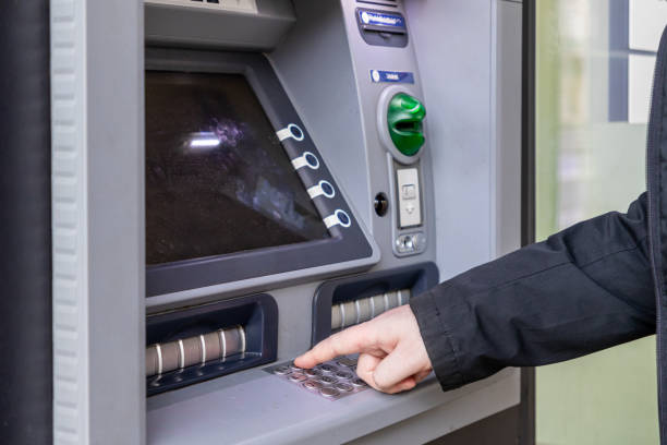 istock person using an atm machine, entering a pin code on the keypad, with a green card slot and a screen in the background, modern banking technology in use 2198576274