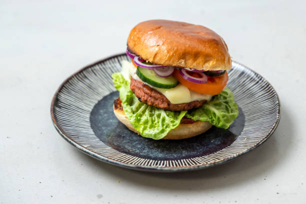 Delicious plant-based cheese burger on brioche bun with fresh vegetables