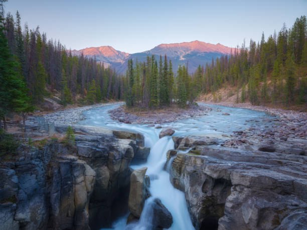 istock High mountains during sunrise. Waterfall among rocks and forest. Rocky Mountains, Canada. Natural landscape. Image for postcards, wallpapers, backgrounds. 2198583679