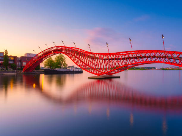 istock The Python Bridge, Amsterdam, the Netherlands. The bridge on the blue sky background during the blue hour. Dutch canals. Reflections on the surface of the water. Photo for background, wallpaper, postcards. 2198583688