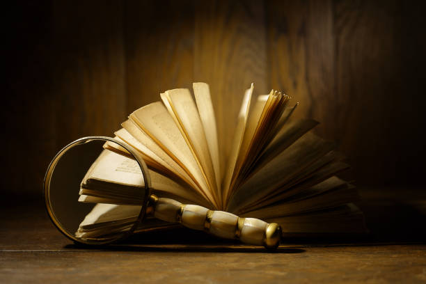 Magnifying glass in front of antique book with open pages. Old ancient open book.