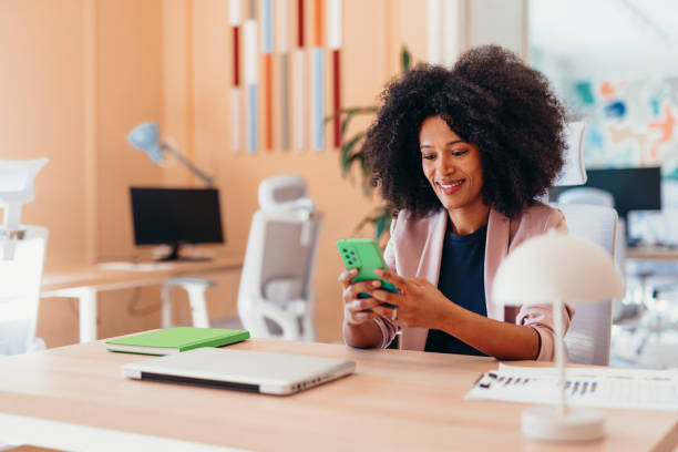 istock Smiling businesswoman using smartphone at her desk in modern office 2198589510