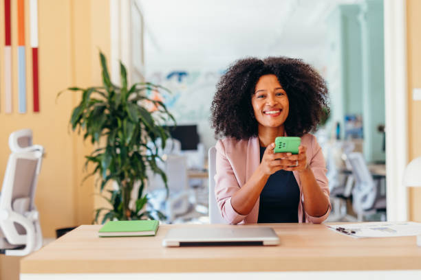 istock Smiling businesswoman using smartphone at her desk in modern office 2198589541