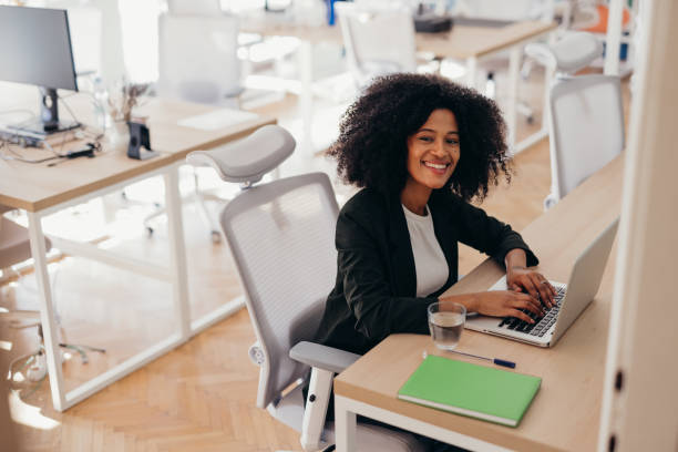 istock Young manager working on laptop in modern office, smiling at camera 2198589732
