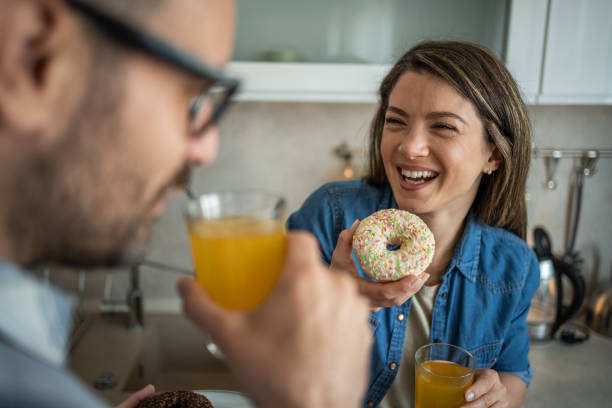 istock Joyful couple savoring doughnuts in the kitchen 2198590592