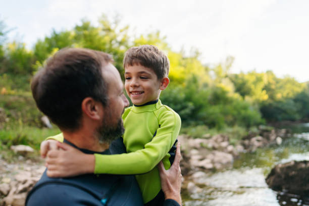 Photo of father and son in wetsuits on the river