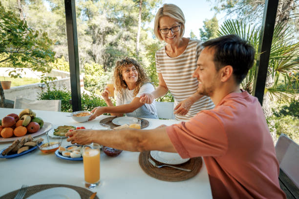 istock Mature woman serving breakfast for young couple at back yard 2198592465