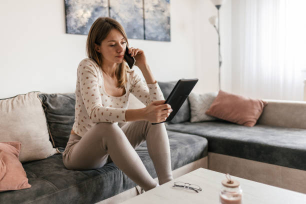 istock Woman relaxing at her home and using a mobile phone and digital tablet 2198599574