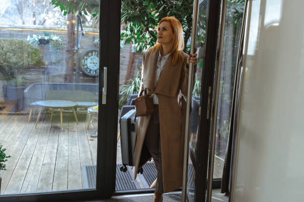 istock Business professional entering a modern home with a suitcase in hand 2198600053