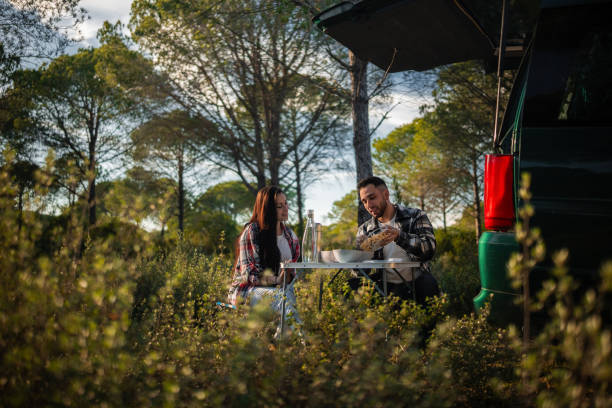 istock Young couple enjoying a meal in nature by their minivan 2198601695