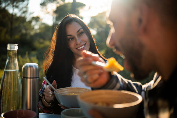 Young couple sharing a meal during a camping trip at sunset