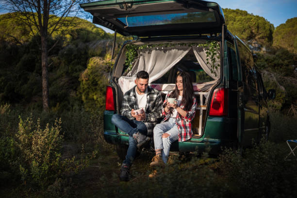 istock Young couple enjoying hot drinks in their camper van during a forest adventure 2198601744