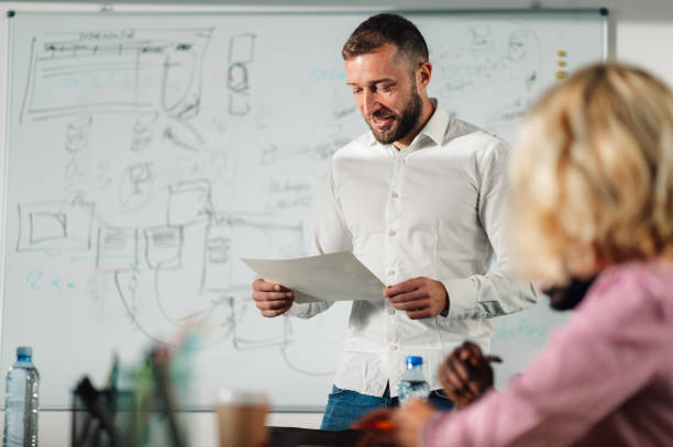 istock Manager reading report to colleagues during office presentation meeting 2198602268