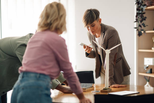 istock Businesswomen planning project with solar panel and wind turbine models 2198602317