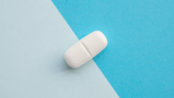 istock White medicine pill tablet on blue and white background 2198602445