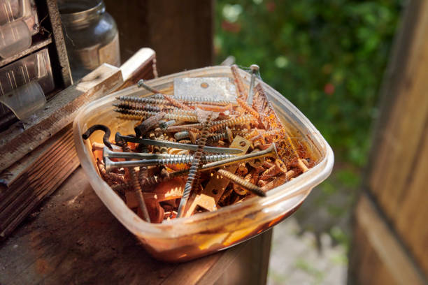 A detailed photograph of a container filled with various rusty screws and tools, highlighting aged metal texture and the vibrant orange of rust, perfect for projects related to repair or industrial themes.