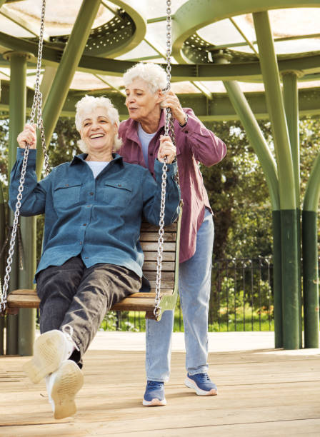 istock A cheerful old sisters is having fun in a summer park swinging on a swing. 2198603681