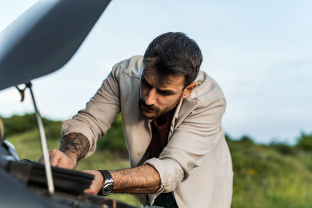 istock Man having car problems and trying to fix his car while checking under the hood 2198603782