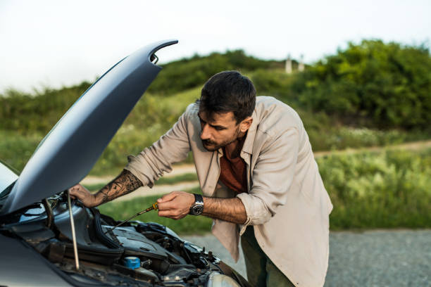istock Man having car problems and trying to fix his car while checking under the hood 2198604128