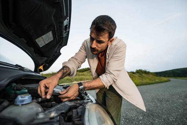 istock Man having car problems and trying to fix his car while checking under the hood 2198604171
