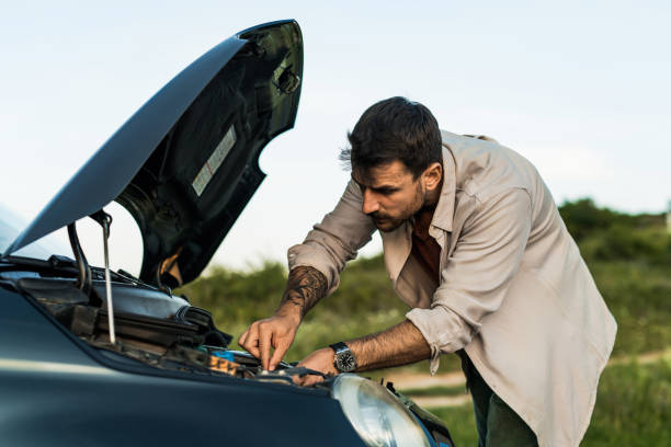 istock Man having car problems and trying to fix his car while checking under the hood 2198604192