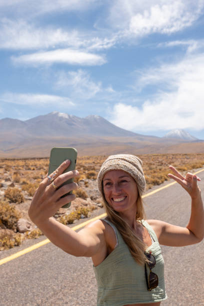istock Woman Taking a Selfie on Desert Highway with Mountain Backdrop 2198604741