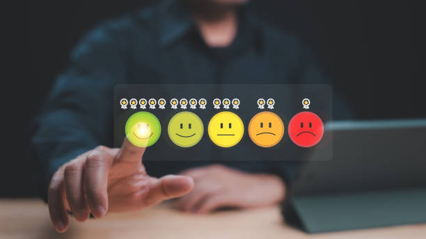 istock User Engagement Feedback via Emoji Rating, Hand interacts with digital emoji rating system, indicating user satisfaction levels through colorful smile faces and red frown 2198604780