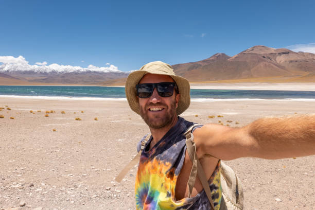 istock Smiling Tourist Taking Selfie at Scenic Desert Lake 2198604941