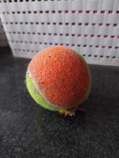 istock An orange and yellow chewable tennis ball on a black surface 2198605538