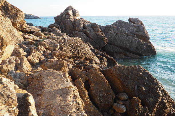 istock Waves gently crash against the rugged rocks while the sun sets over the horizon. Experience the serene beauty of this coastal location filled with natural wonders. Canj, Montenegro, Adriatic sea 2198612692