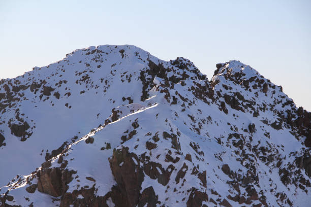 istock Snow-covered rocky mountain peaks under clear sky. 2198614807
