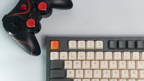 istock Mechanical Keyboard and Black Gamepad.  Low violet light. The concept of computer games, entertainment, gaming, leisure. Close view. 2198620597