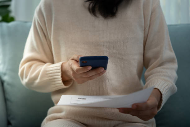 istock woman use phone scan barcode or QR codes to pay credit card bill after receiving document invoice. payment, receive, paying electricity, digital payments, technology, scanning, financial transactions 2198624269