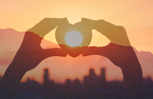 Heart in hand over city sunset, Love symbol