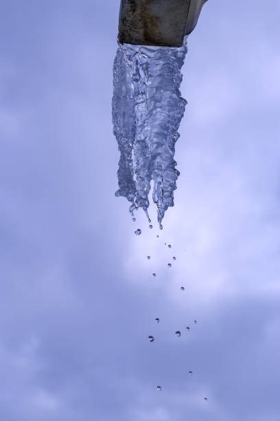 Icicle hanging on drainpipe from roof of house.