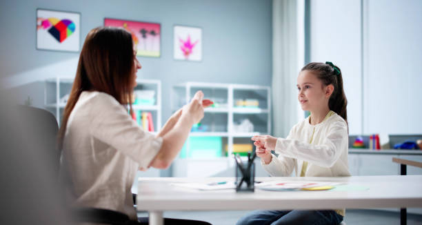 istock Little girl learns sign language from hearing disability teacher 2198632494