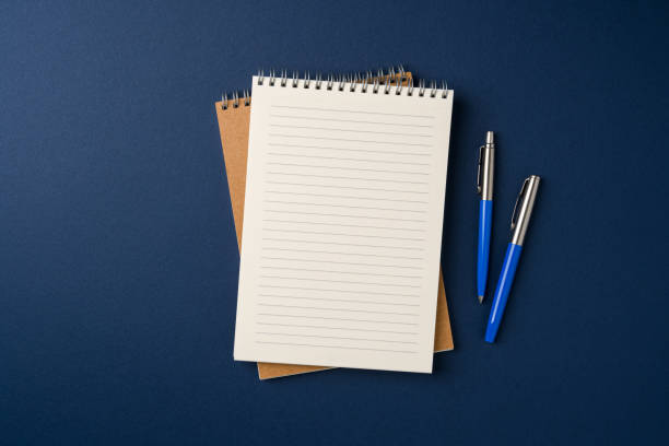 Top view of notebook and ballpoint pen on blue background