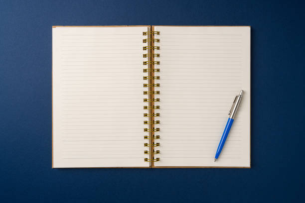 istock Top view of notebook and ballpoint pen on blue background 2198635137