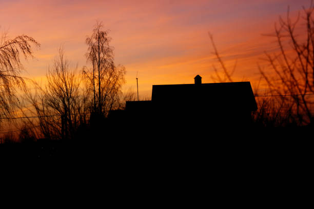 istock A house with a chimney is silhouetted against a beautiful sunset 2198636439