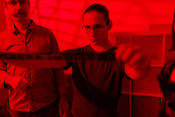 Students learning to develop photos in dark room under the mentorship of a professor