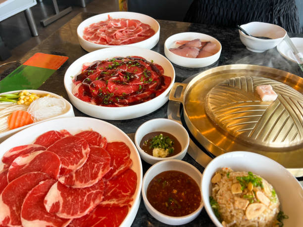 istock Korea BBQ style restaurant. Asian traditional pickle vegetable ingredients on table with people grilling background. 2198639525