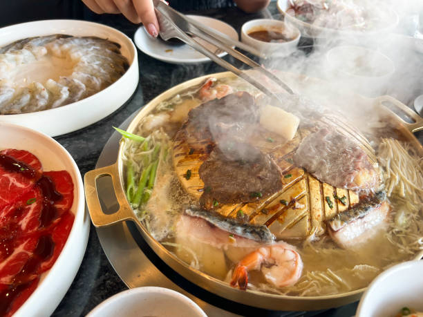 istock Korea BBQ style restaurant. Asian traditional pickle vegetable ingredients on table with people grilling background. 2198639537