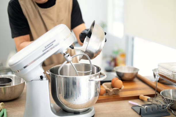 istock Male baker pouring ingredients into a stand mixer for cookie dough 2198639656