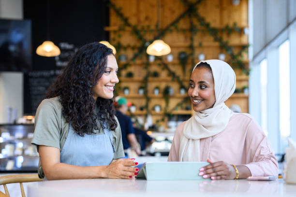 istock Cafe owner and Middle Eastern woman smiling at each other using digital tablet together 2198644015