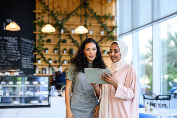 istock Cafe owner standing with financial adviser looking at digital tablet 2198644050