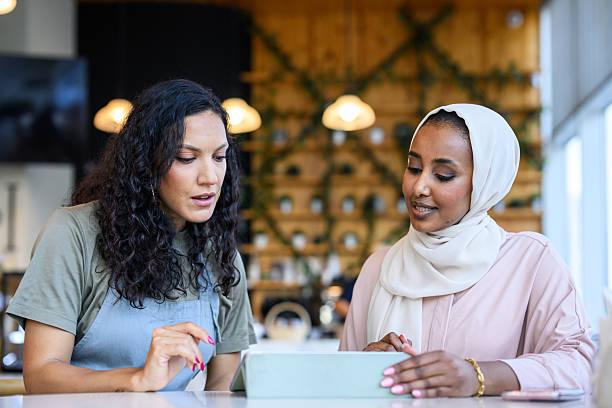 istock Focused women reviewing strategy on digital tablet at cafe 2198644052