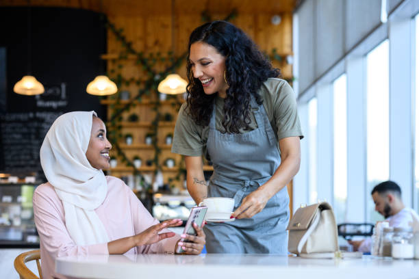 istock Waitress serving hot drink to Middle Eastern woman in cafe 2198644083