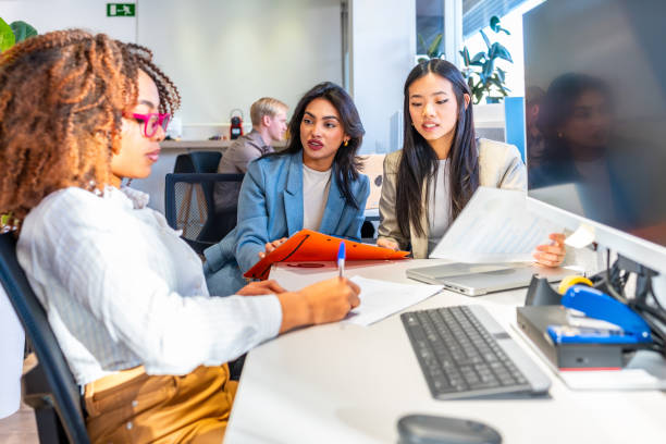 istock Businesswomen collaborating on project in coworking office analyzing documents 2198645988
